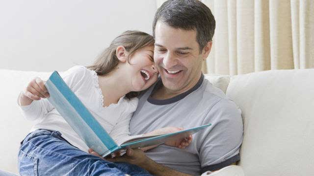 Father and small daughter reading book